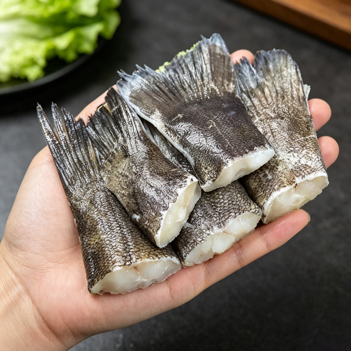 Several raw cod tails held in one hand