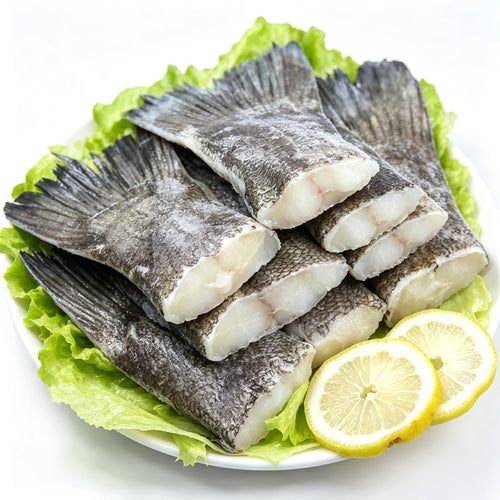 Raw cod tails arranged on a plate with lemon
